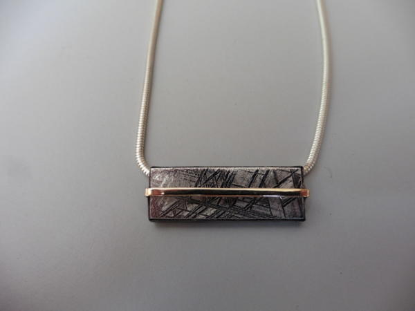 Pendant commission 2018.  Meteorite slice set in silver with gold bar on silver snake chain.